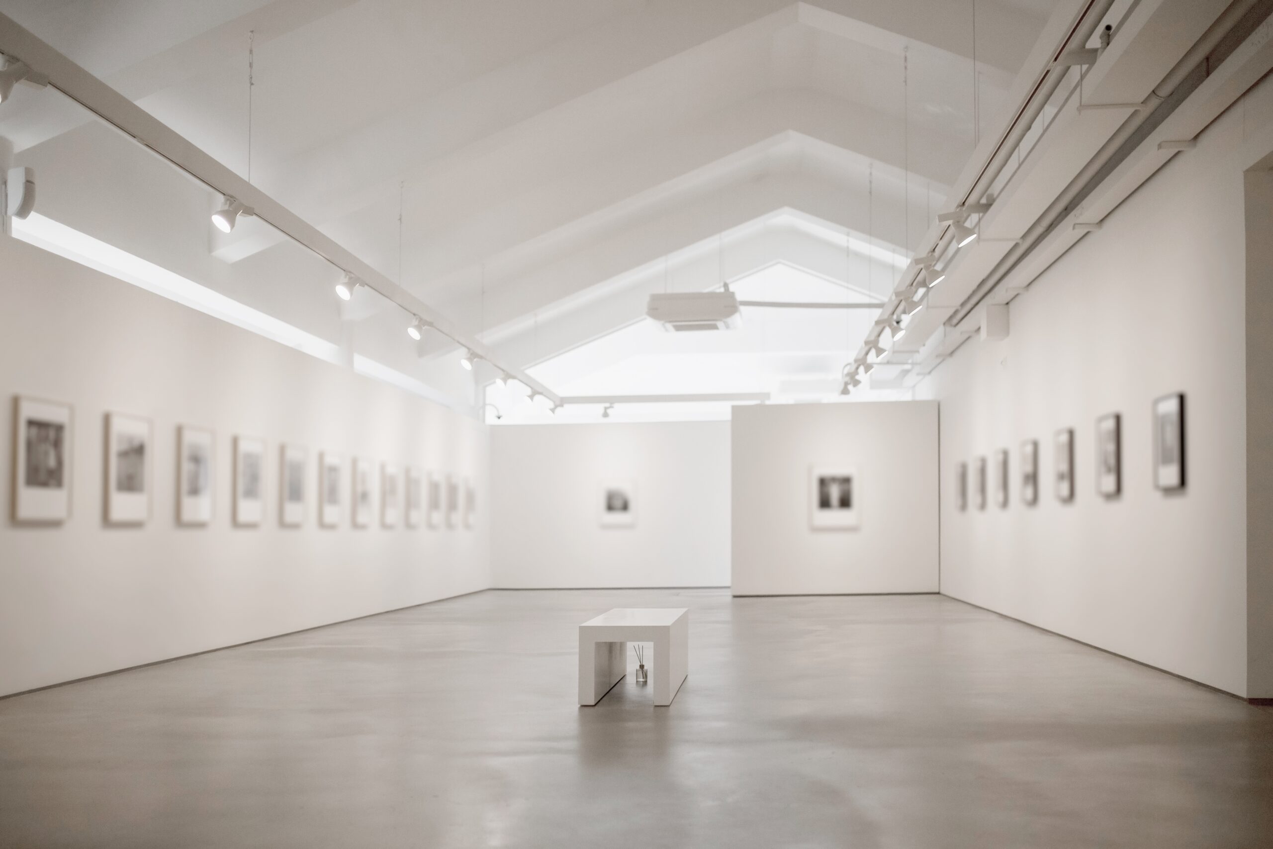 Framed artwork lines a long white well lit exhibition hall.  